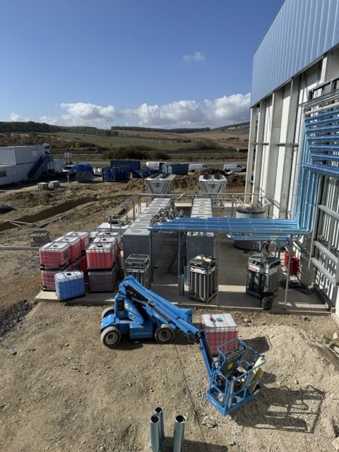 Plateforme technique extérieure d'un site de froid industriel en chantier, réseaux bleus en façade