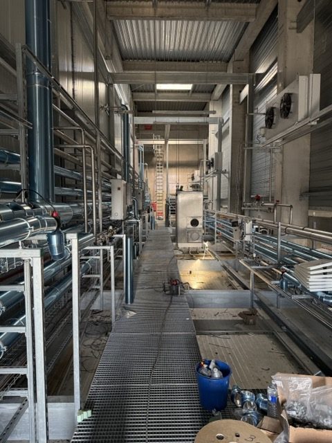 Salle des machines en chantier : passerelle caillebotis et réseaux de tuyauterie de part et d'autre